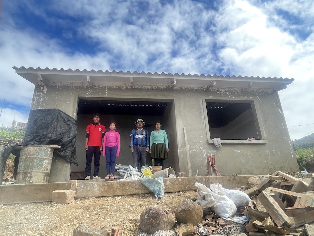 A family standing in front of their house in Bolivia, built by BUYONE BUILDONE.