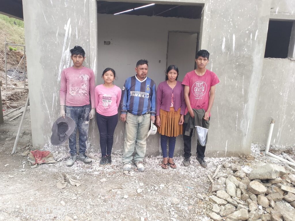 A family standing in front of their house in Bolivia, built by BUYONE BUILDONE.
