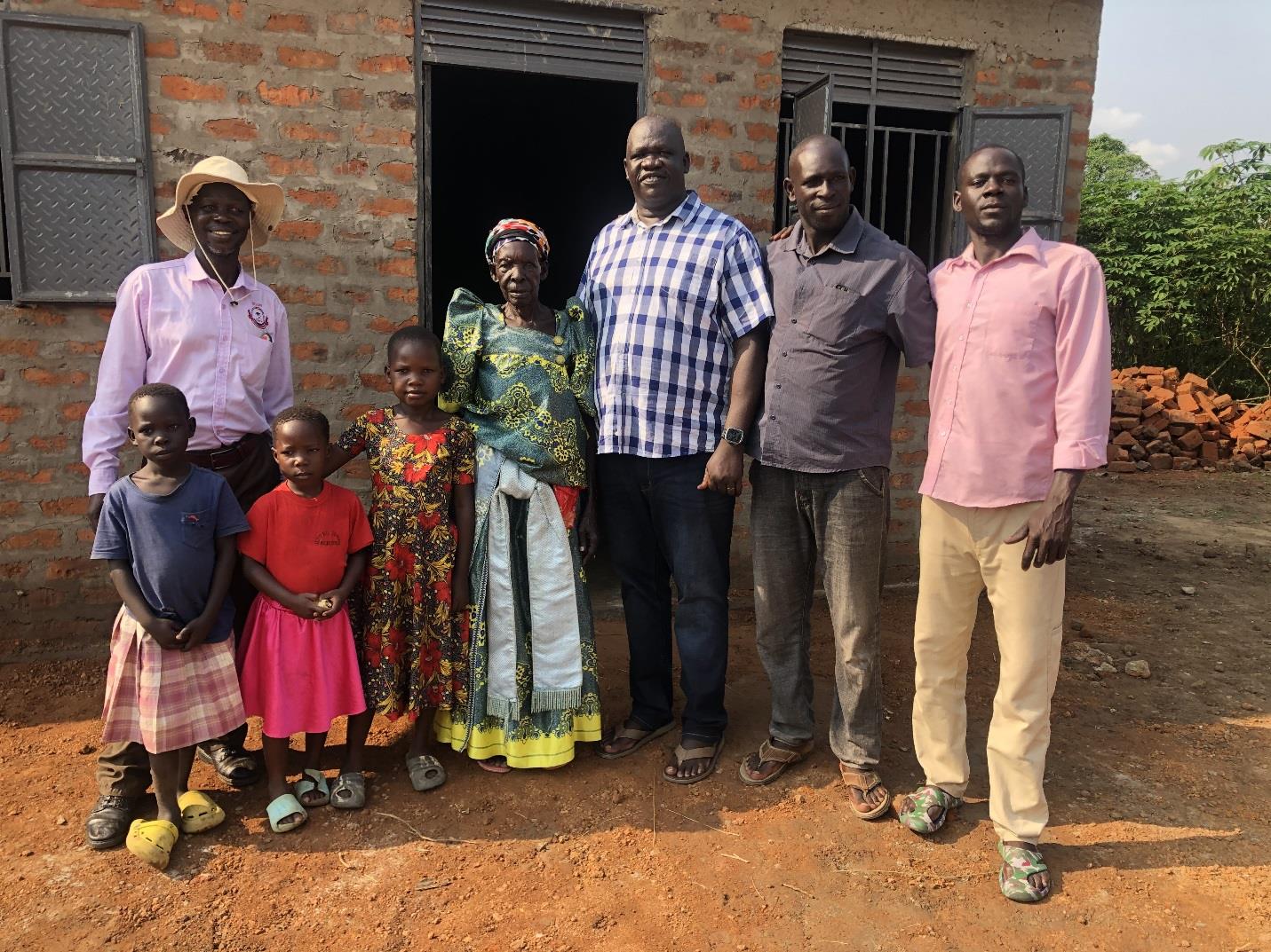 A family standing in front of a house in Uganda.