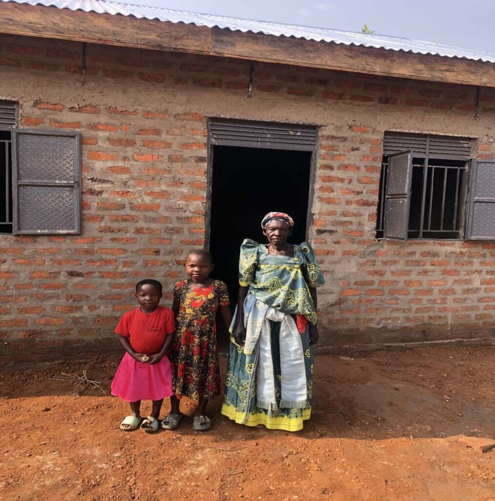 A family standing in front of a house in Uganda.