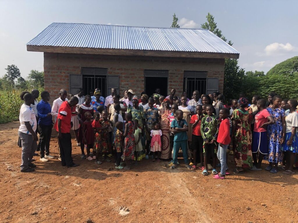 A community of people in front of a house in Uganda.